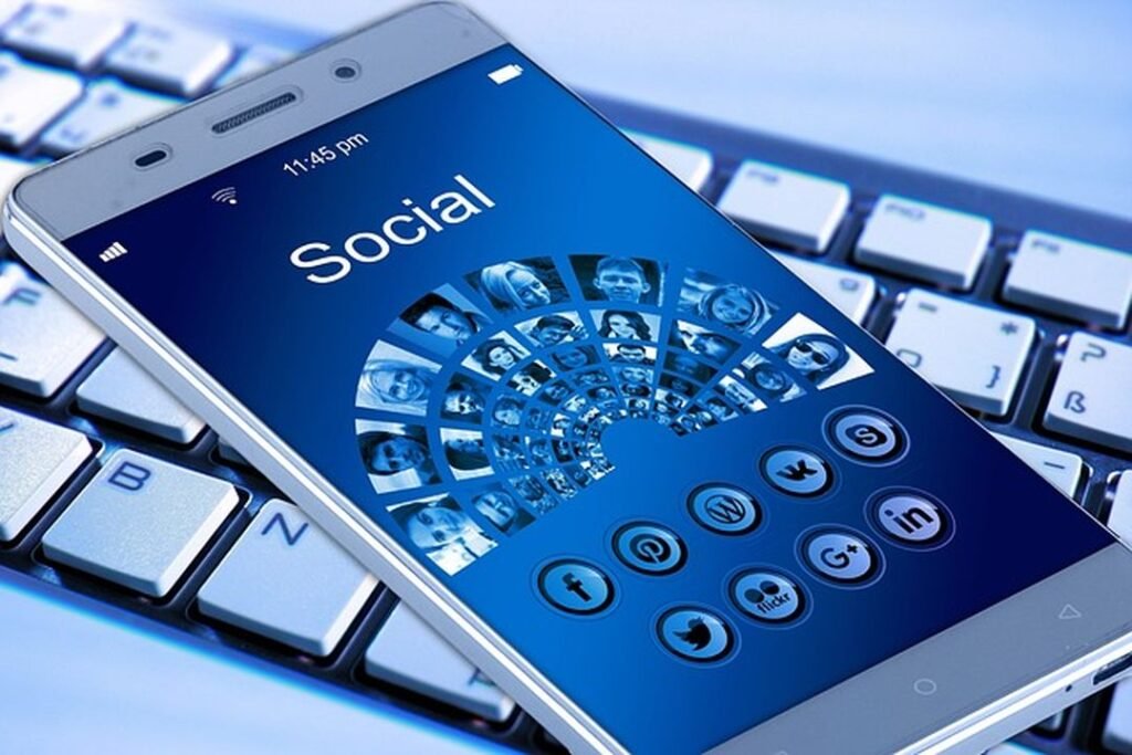 Una imagen con un teléfono móvil mostrando diversas redes sociales y una mano presionando un botón de "compartir"